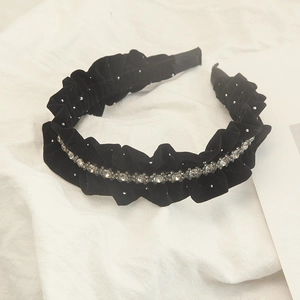 Close-up of black velvet headband with pleated texture and sparkling rhinestones