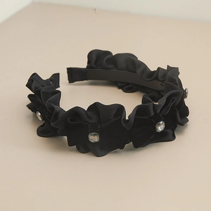 Détail d'un serre-tête en satin plissé noir avec strass brillants et doublure antidérapante