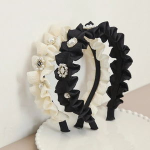 Detail of pleated fabric headbands with elegant pearl flower and rhinestone accents