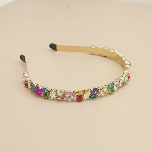 Détail macro de pierres précieuses colorées et strass sur serre-tête en métal doré