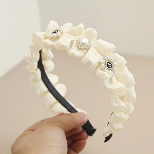 Detail of cream pleated headband featuring pearls, crystals, and a vintage number 5 charm