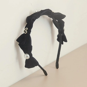 Détail du serre-tête en velours noir avec nœuds, perles et pendentif cœur en strass