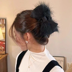 Detail view of large black ostrich feather bow hair claw clip worn on model hair