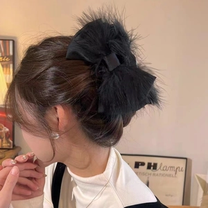Detail of elegant black ostrich feather bow hair claw clip worn on a woman's hair