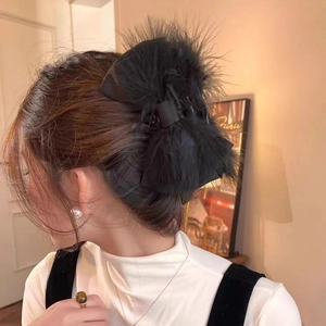 Close-up of black ostrich feather bow hair claw clip worn on model's hair in elegant style