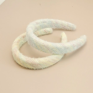Détail de deux serre-têtes en peluche à carreaux aux tons macaron et texture fausse fourrure