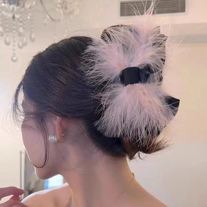 Detail of pink ostrich feather bow hair claw clip worn on a woman's hair back view