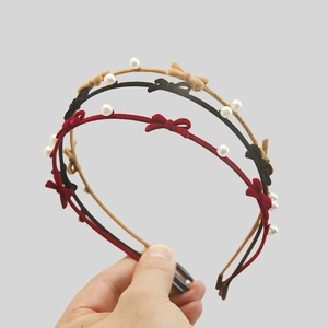 Detailed close-up of three velvet headbands with bows and pearls in red, black, and beige