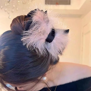 Detail of pink ostrich feather bow hair claw clip styled on a low bun hairstyle