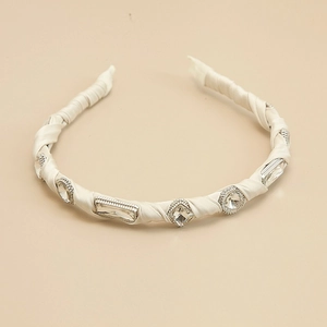 Detailed macro view of cream satin headband with sparkling crystal embellishments