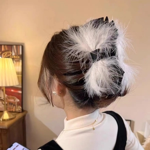 Detailed view of elegant white ostrich feather hair claw with black satin bow on model