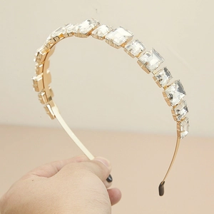 Détail du serre-tête en métal doré avec cristaux brillants et embouts de protection