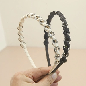 Dettaglio di cerchietti con strass scintillanti neri e crema con cristalli a forma di pera