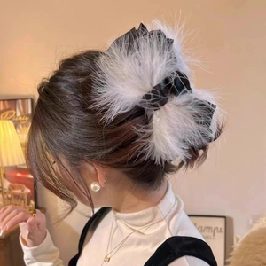 Close-up of a large black satin bow hair claw with fluffy white ostrich feathers