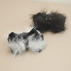 Detail view of large bow hair clips with fluffy ostrich feathers and satin texture