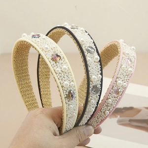 Detailed close-up showing hand-stitched pearls and colorful crystals on wide velvet headbands