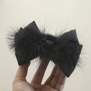 Macro detail of the black bow hair claw with elegant ostrich feathers and matte satin finish
