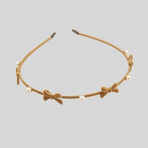 Detail of khaki velvet headband featuring small bows and elegant white faux pearls
