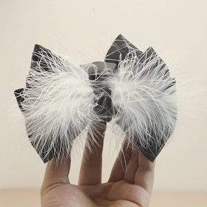 Detail of large black satin bow hair claw with fluffy white ostrich feathers