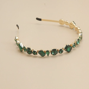 Détail d'un serre-tête doré orné de cristaux vert émeraude aux diverses formes géométriques
