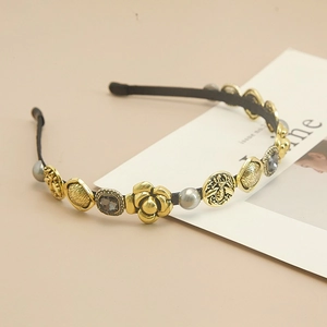 Detail view of Baroque headband featuring gold camellias, pearls, and bee coins
