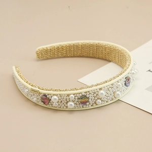 Detail of wide headband featuring white pearls, crystals, and a gold LOVEDAYS metal tag