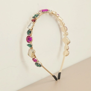 Détail d'un serre-tête en métal doré avec strass multicolores et embouts de protection