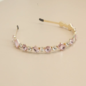 Détail de strass en cristal rose et blanc sur un serre-tête en métal doré élégant