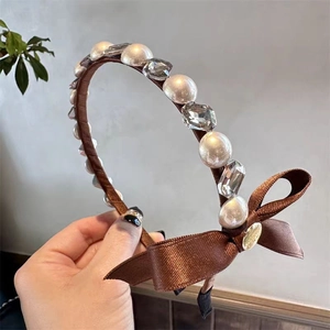 Detail of satin headband featuring elegant pearls, crystals, and a side ribbon bow accent