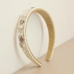 Detail of beaded headband with white pearls, colored crystals and a small metal logo plate