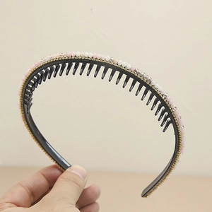 Détail d'un serre-tête noir avec perles roses et blanches et dents de peigne internes