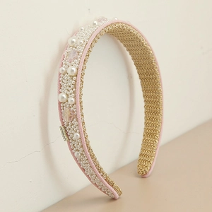 Detail of pink fabric headband featuring faux pearls, beads, and gold metal brand tag