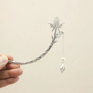 Detailed shot of silver rose hairpin featuring white gemstone and pearl tassel drop