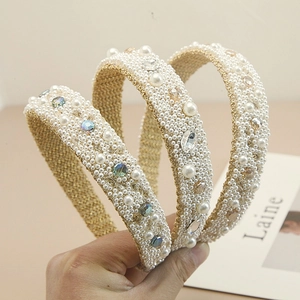 Close-up of a wide headband featuring densely inlaid white pearls and sparkling rhinestones