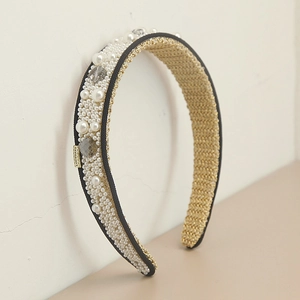Detailed macro view of white pearls, crystals and gold woven lining on the hairband