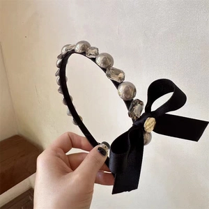Detailed shot of bow headband with pearls and engraved Believe in Yourself metal tag