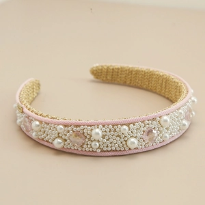 Close-up of pink fabric headband with white faux pearls and multifaceted crystals detailing