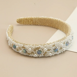 Close-up of baroque wide headband with white pearls and faceted iridescent crystals