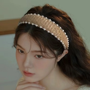 Detail view of gold-brown tweed headband with white pearls and sparkling texture
