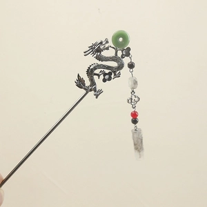 Detailed close-up of a silver dragon hair stick with green jade and elegant tassels