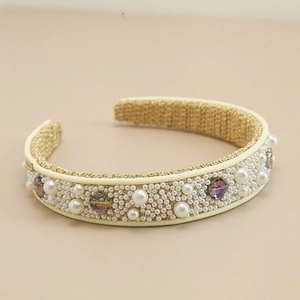 Detailed shot of wide headband with pearls and multicolored crystals on woven base