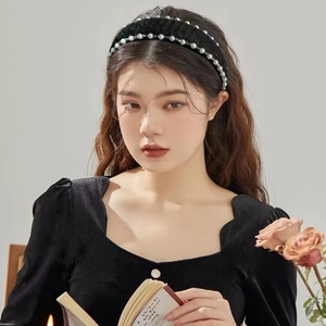Detailed macro view of black velvet wide headband featuring double rows of white pearls
