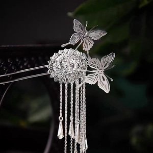 Detail of silver butterfly hair pin with ornate hollow flowers and long tassel chains