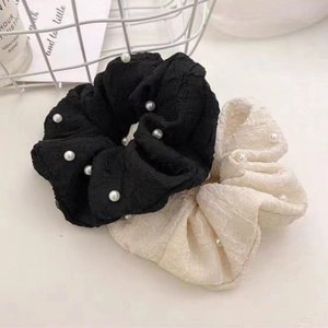 Détail de chouchous élégants noirs et crème plissés avec décor de perles blanches