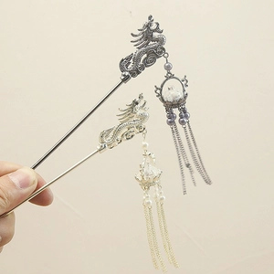 Detailed view of traditional dragon tassel hair pins in silver and gold metal finishes