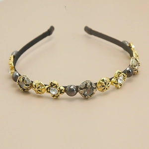 Detailed macro view of baroque hair hoop featuring vintage gold crosses and pearls