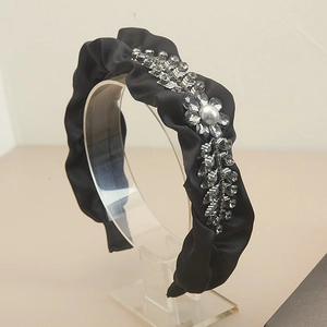 Detail of black pleated satin headband with rhinestone leaves and a blue pearl inlay