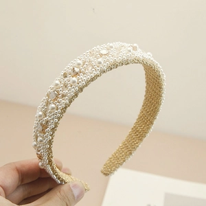 Detailed close-up of handmade baroque headband with white pearls and champagne crystals