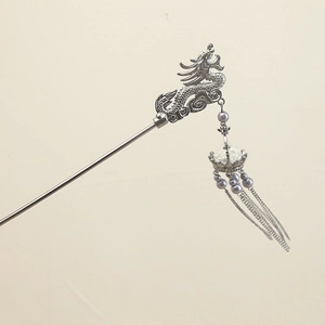 Detailed close-up of a vintage silver dragon hairpin with purple beads and metallic tassels