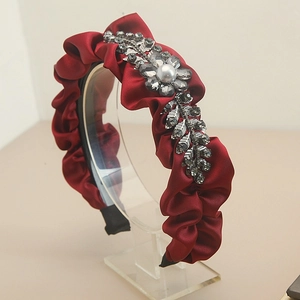 Detail of burgundy pleated satin headband with rhinestone leaf and pearl accent